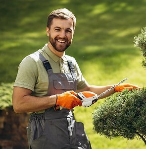Professional landscape gardener pruning hedges in Muscat